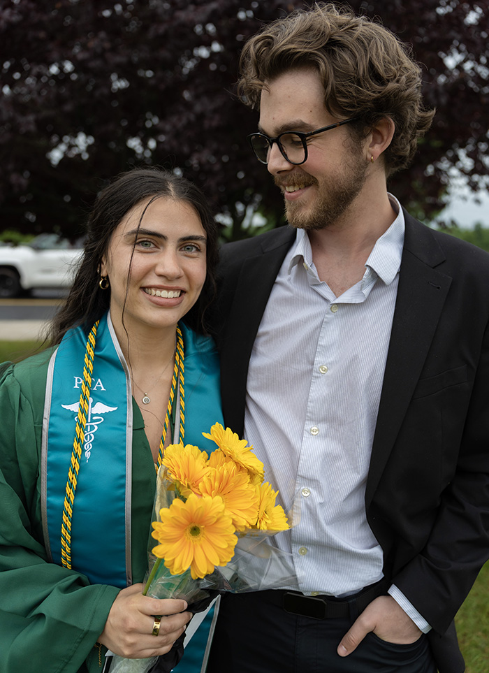 A graduate posing happily for a portrait with their family after the ceremony