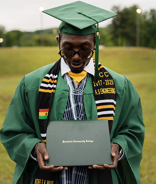 A group portrait of smiling graduates holding up their diploma covers together