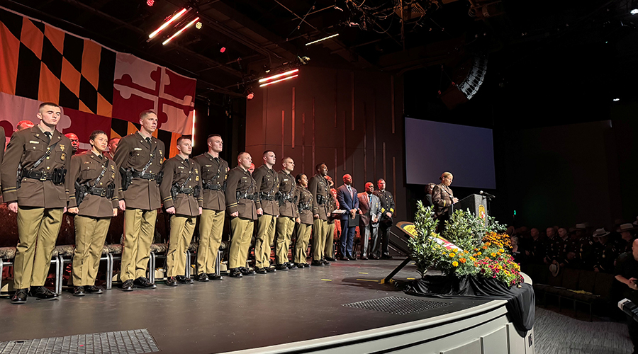 Graduates of the Maryland State Police 159th Trooper Class are joined on stage by Governor Wes Moore.